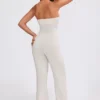 Jumpsuit i grovstickat tyg med bandeau-halsringning och utsvängda byxben i krämfärg