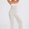 Jumpsuit i grovstickat tyg med bandeau-halsringning och utsvängda byxben i krämfärg