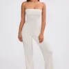 Jumpsuit i grovstickat tyg med bandeau-halsringning och utsvängda byxben i krämfärg